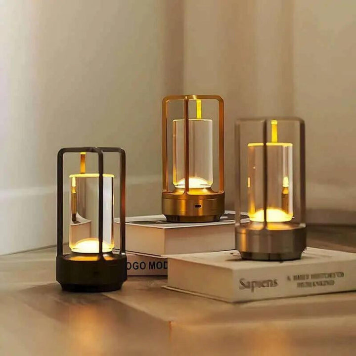 Three Nordic-style crystal table lanterns with warm ambient glow, one black, one gold, and one silver.