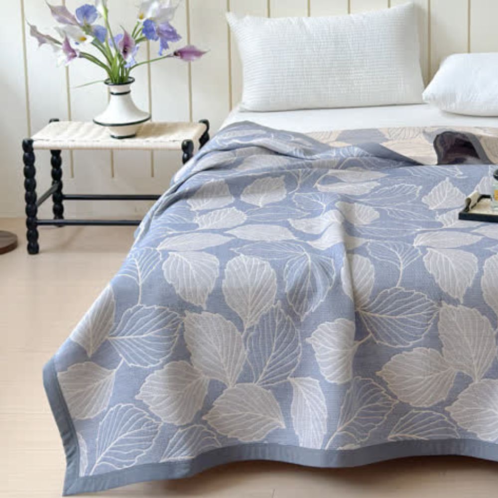 Blue and white mulberry leaf cotton triple gauze blanket draped on a bed.