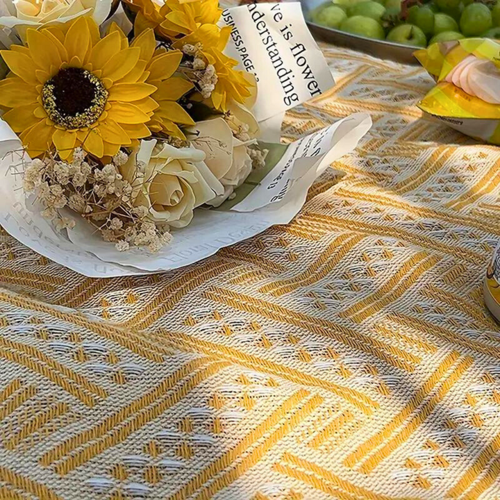 Yellow and white geometric pattern picnic mat with a bouquet of sunflowers and roses.