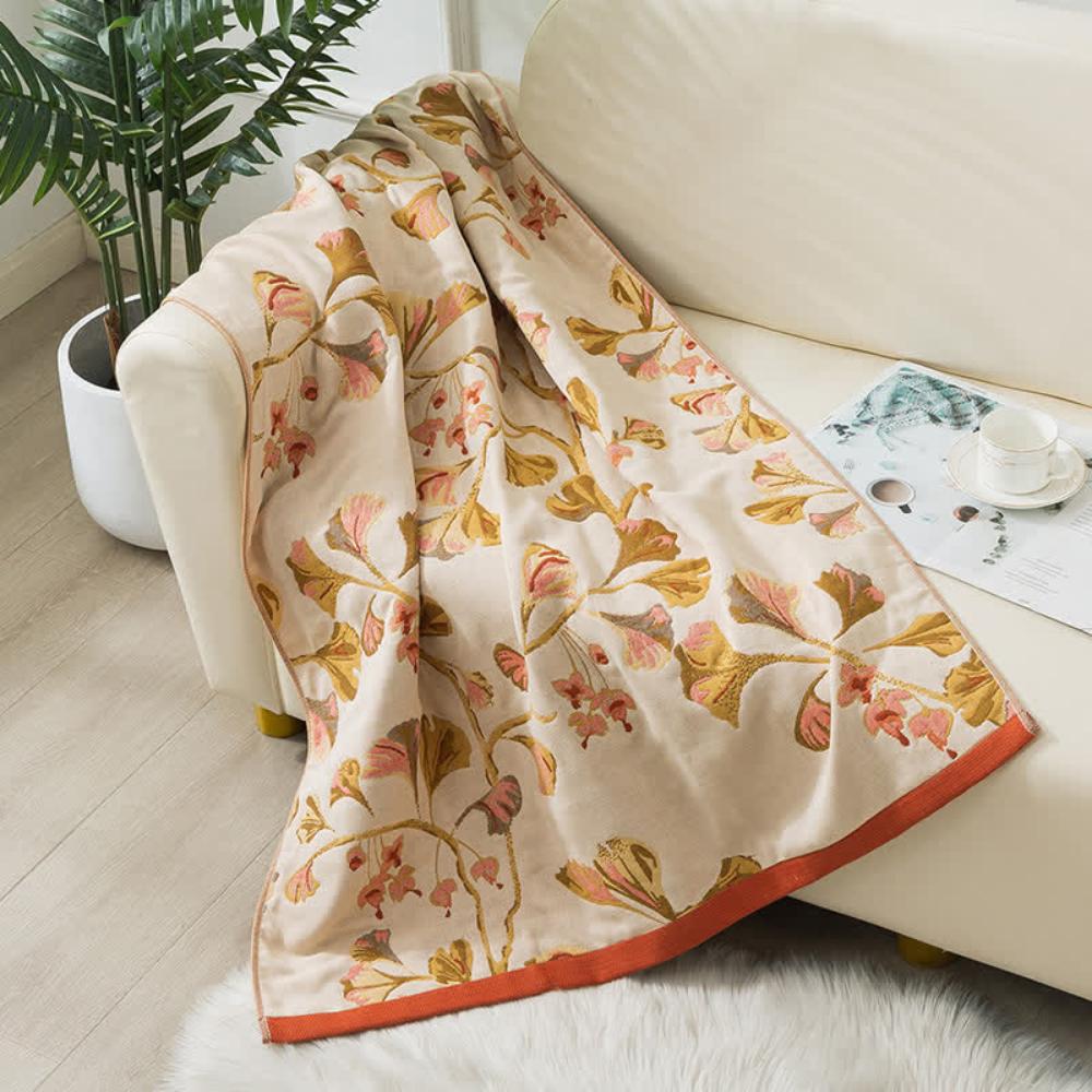 Beige cotton gauze towel with a ginkgo leaf print in shades of pink and gold, and an orange border.