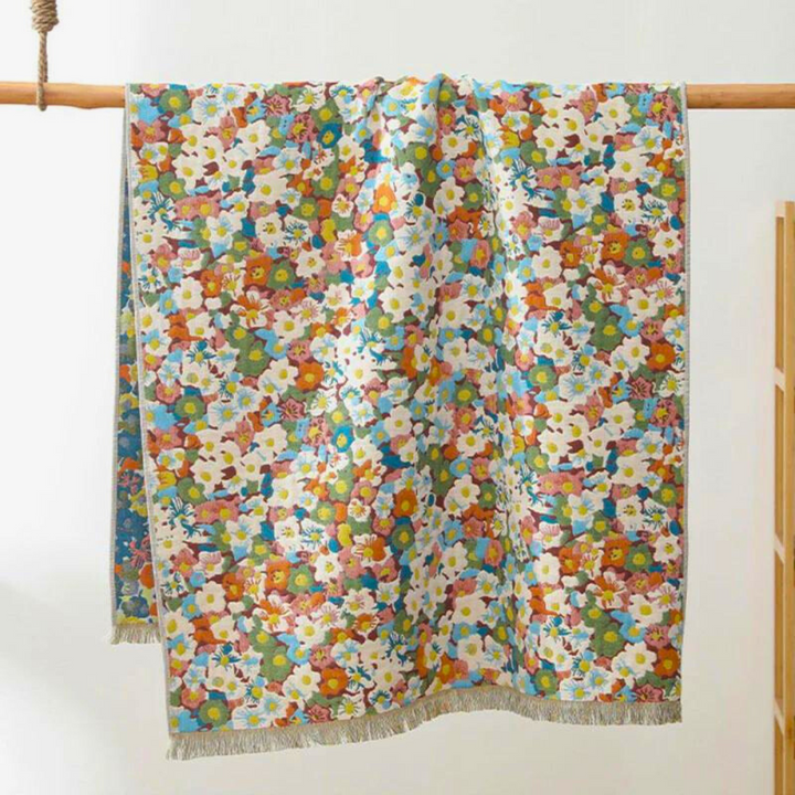 Reversible cotton bath towel with a vibrant, all-over floral print in shades of pink, blue, orange, and green.