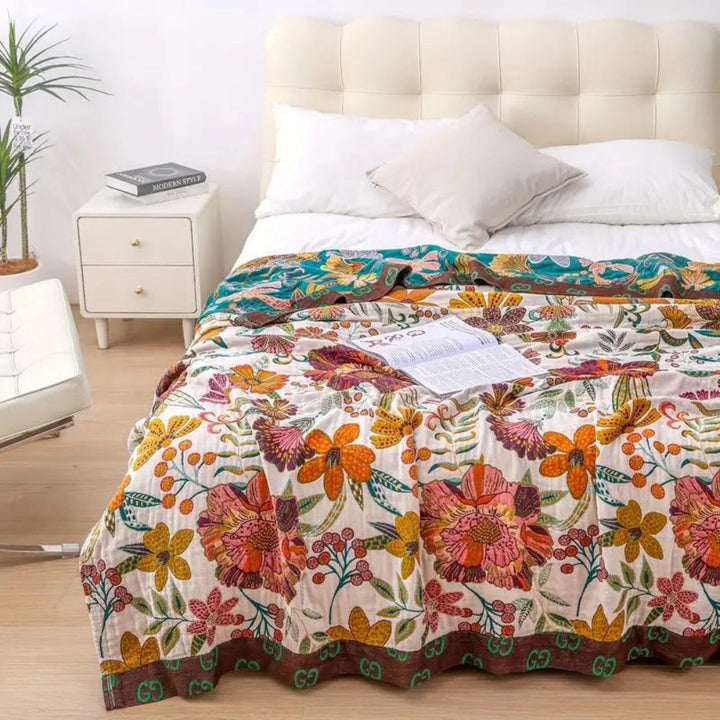Charm floral blanket throw with a colorful floral pattern and a brown border with repeating logos.