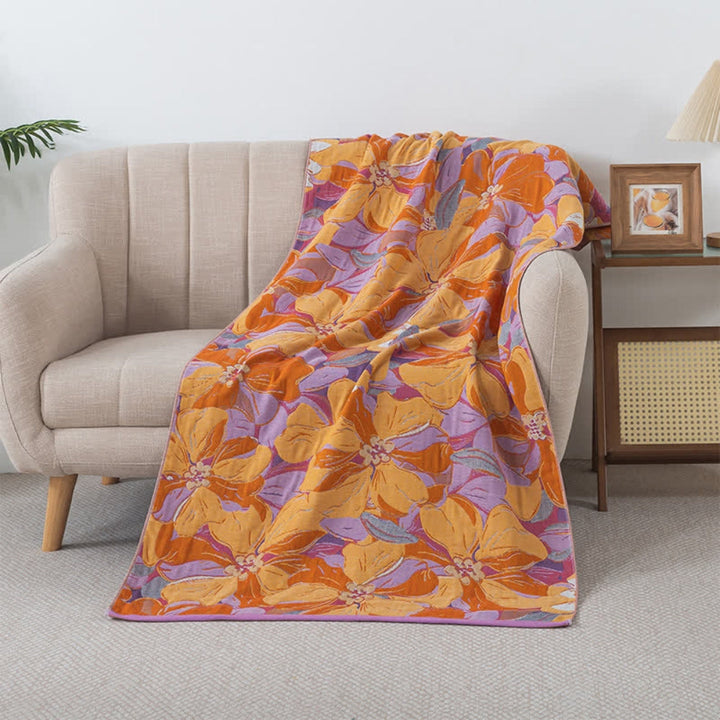 A soft, floral-patterned cotton gauze bath towel draped over a sofa.