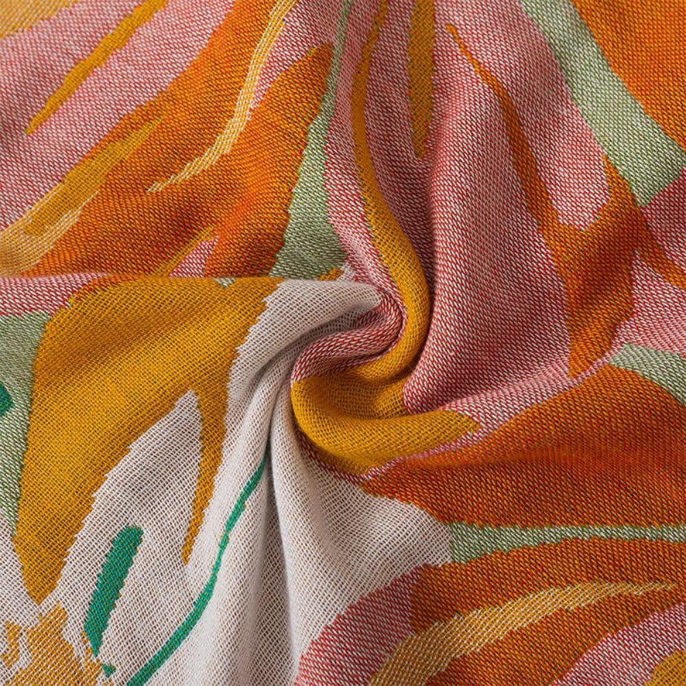 Cotton gauze bath towel with a colorful abstract floral pattern in shades of orange, yellow, pink, and green.