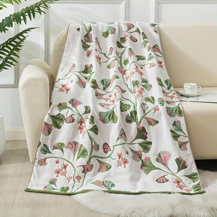 White cotton bath towel with a repeating pattern of pink and green floral leaves.