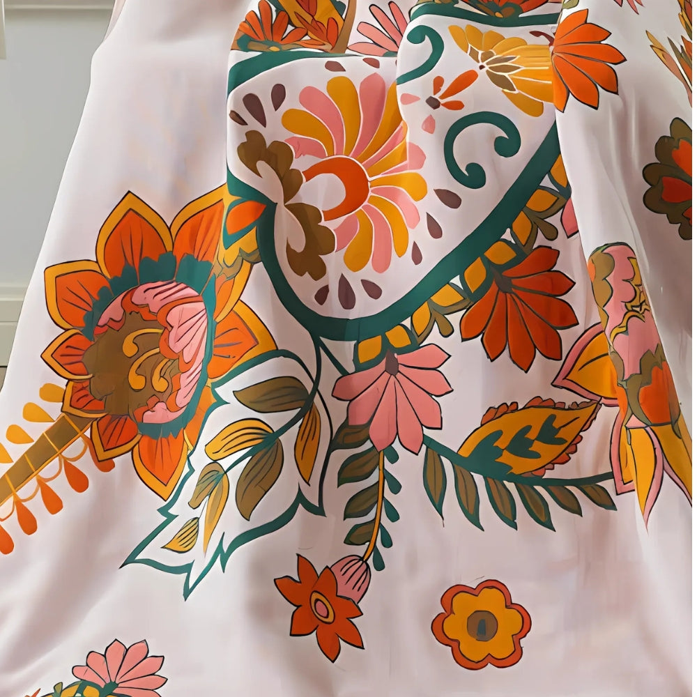 White cotton gauze bath towel with a large, colorful floral print in shades of orange, pink, yellow, and green.