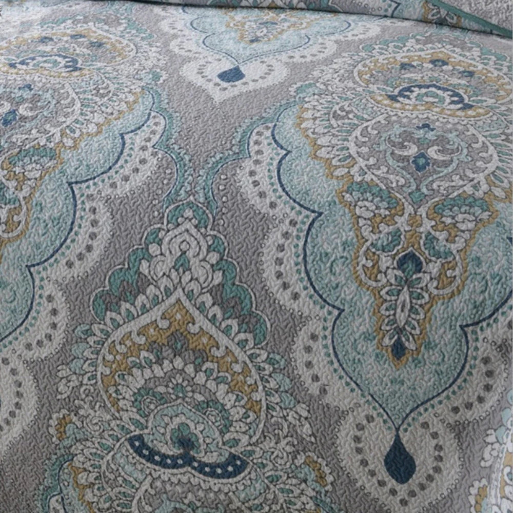 Paisley pattern in aqua, teal, and gray on a quilted coverlet.