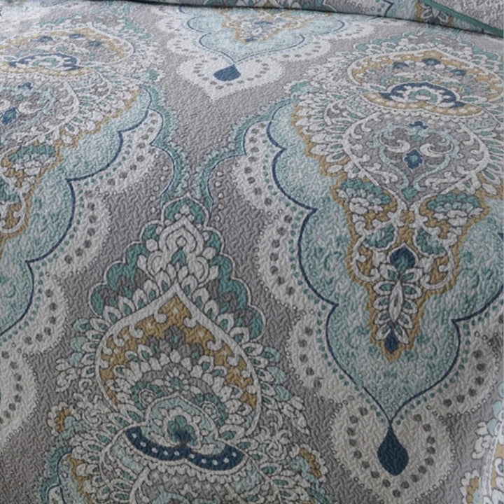 Paisley pattern in aqua, teal, and gray on a quilted coverlet.
