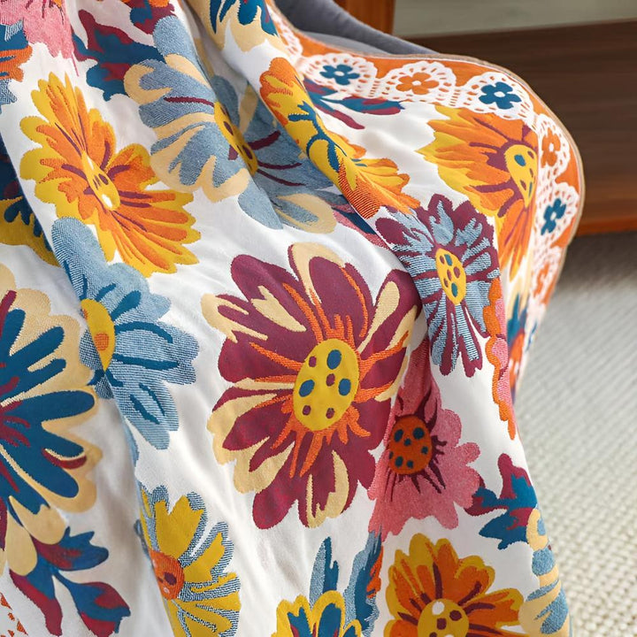 White bath towel with a vibrant, reversible floral pattern in shades of orange, yellow, blue, and burgundy.
