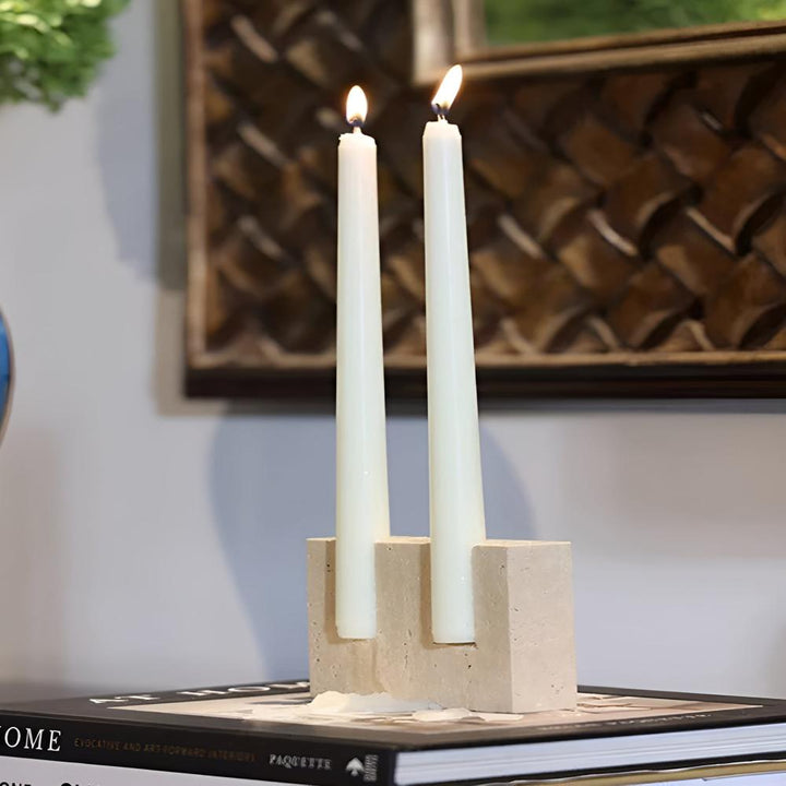 Travertine stone candle stand holding two white taper candles.