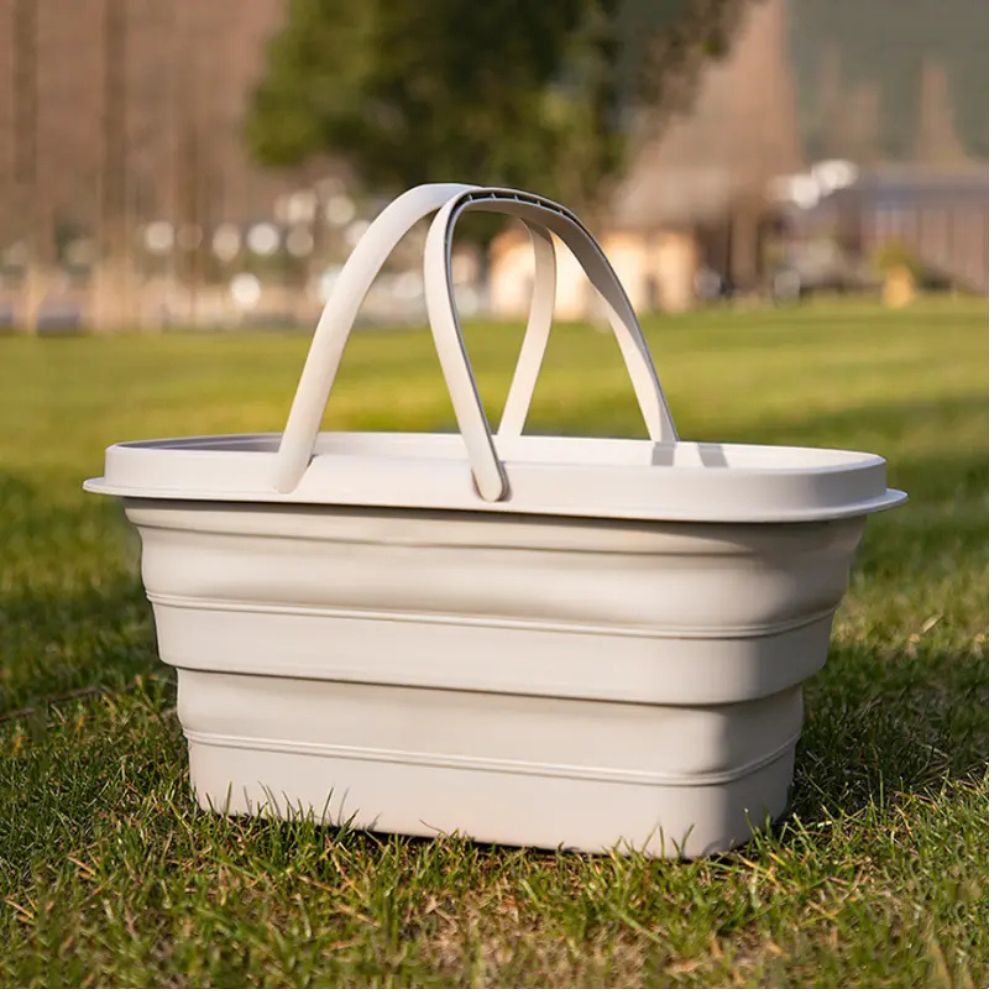 Collapsible storage basket with handles on grass.
