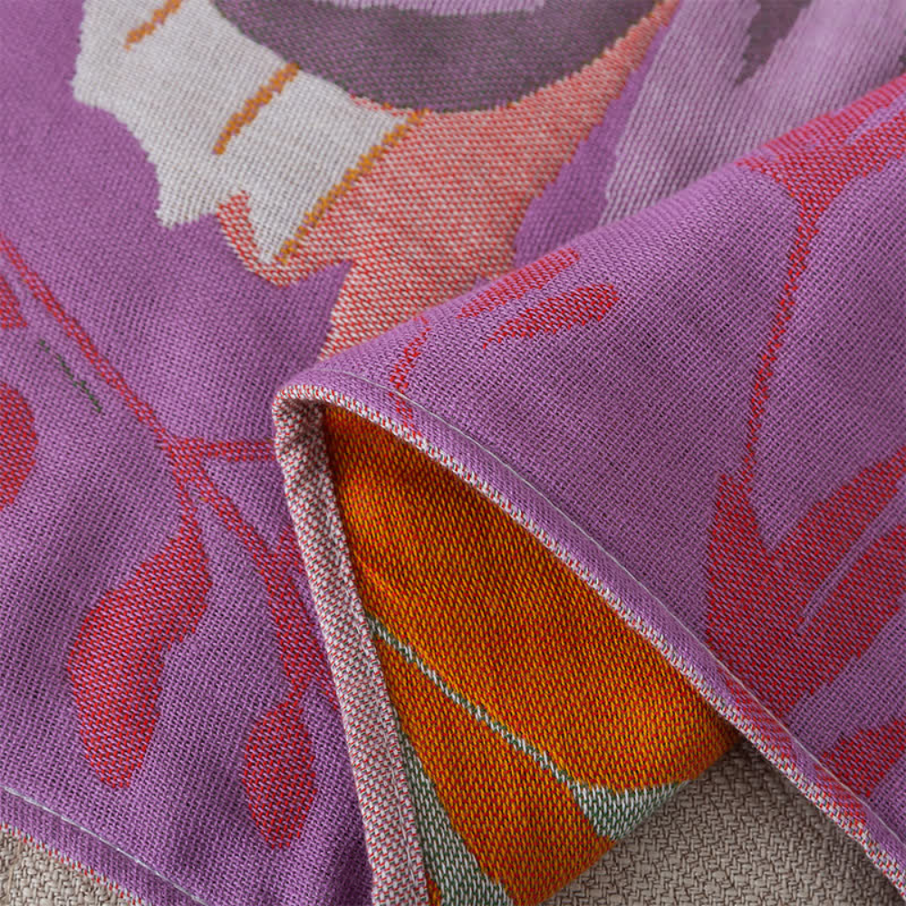 Purple cotton gauze towel with a floral pattern in pink, orange, and white.