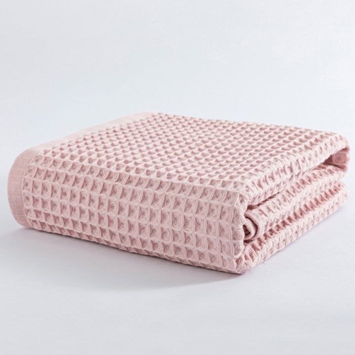 Pink cotton waffle weave bath towel folded on a white background.