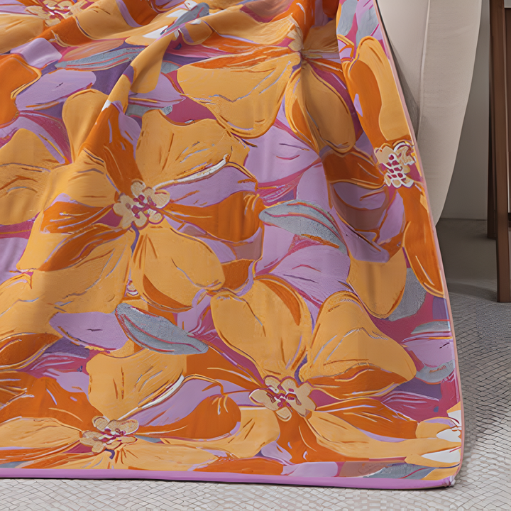 A microfiber bath towel with a vibrant floral pattern in orange, pink, and purple.