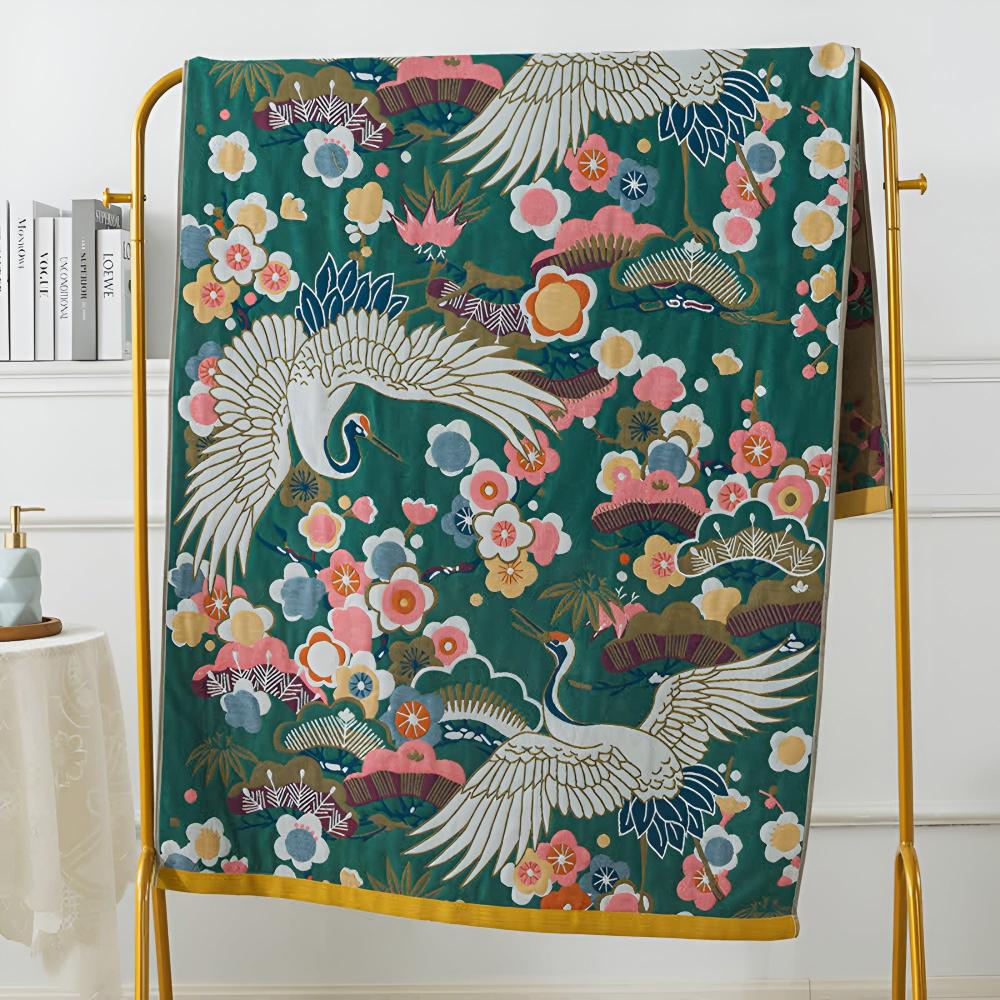 Green cotton bath towel with a Japanese-inspired print of white cranes and pink, yellow, and blue flowers.