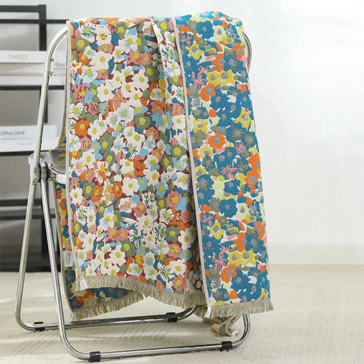 Two reversible cotton bath towels with colorful floral prints draped over a metal chair.