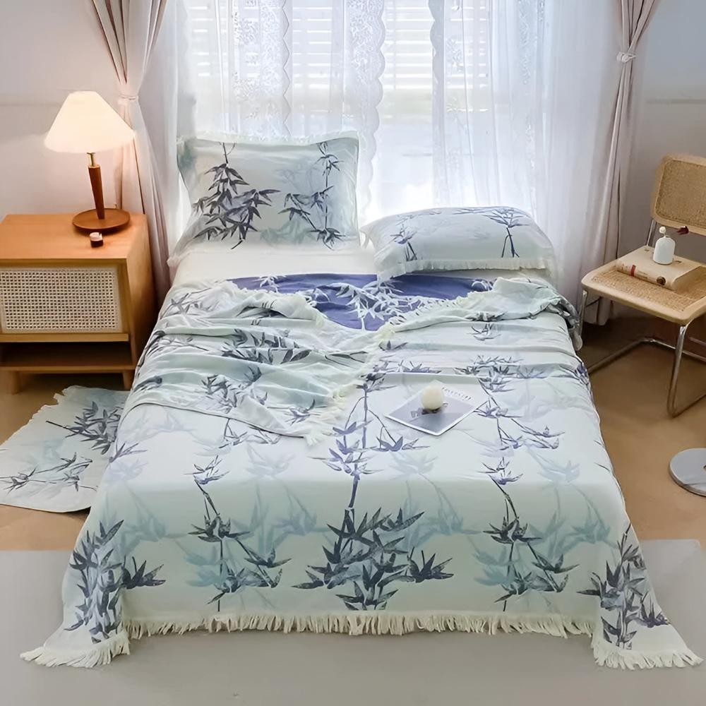 Bamboo Cotton Reversible Jacquard Throw with a blue bamboo leaf pattern and fringe detail on a bed.