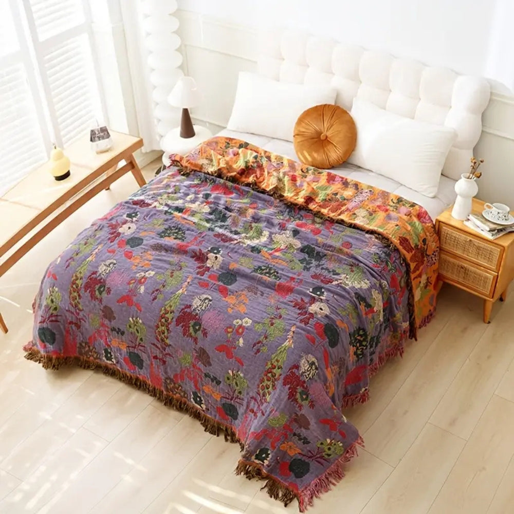 Botanic floral cotton tassel blanket in orchid bloom with purple and orange floral patterns and fringe.