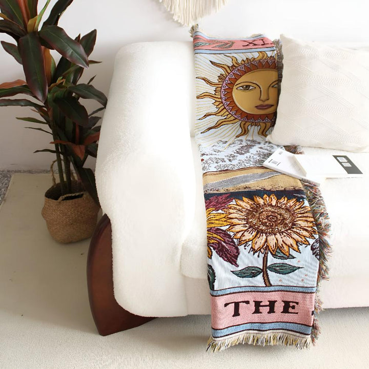 Boho style tapestry throw with a sun and sunflower design draped over a white couch.