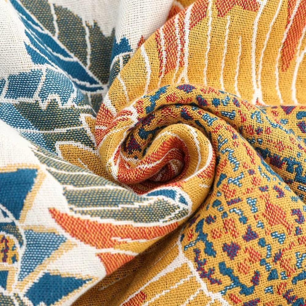 Close-up of a rolled cotton bath towel with a yellow, blue, and orange sunflower jacquard woven pattern.
