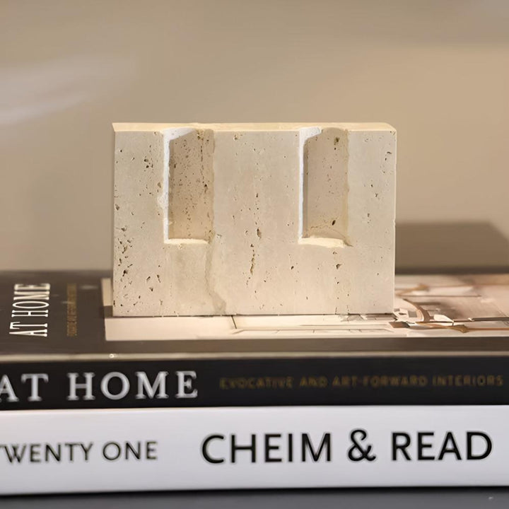 Travertine stone candle stand with two slots for taper candles, placed on books.