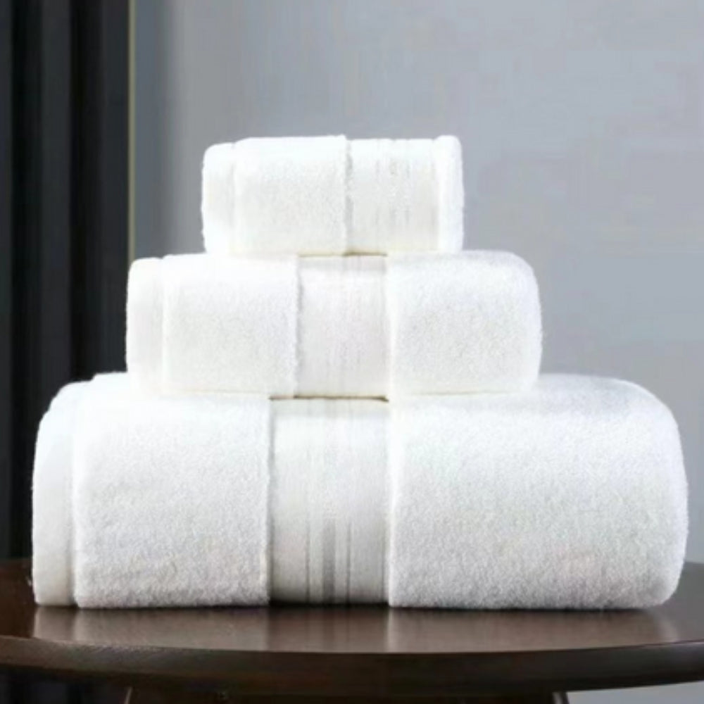 Three white Egyptian cotton towels stacked on a wooden surface.
