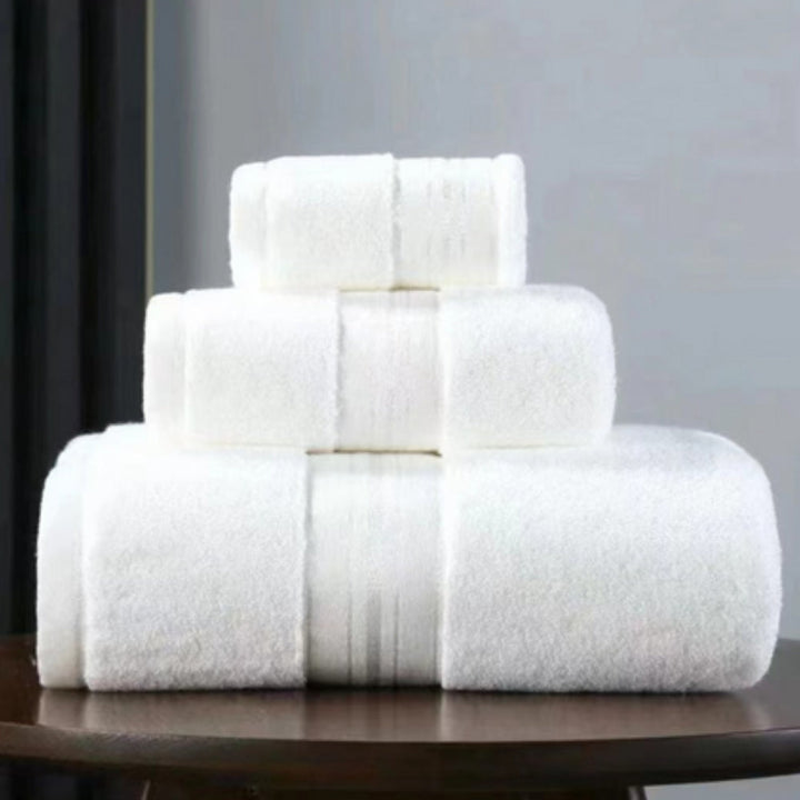 Three white Egyptian cotton towels stacked on a wooden surface.