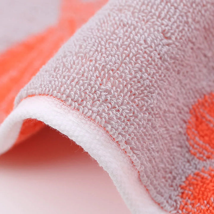 Close-up of a soft, pure cotton bath towel with a textured weave and an orange ginkgo leaf pattern.