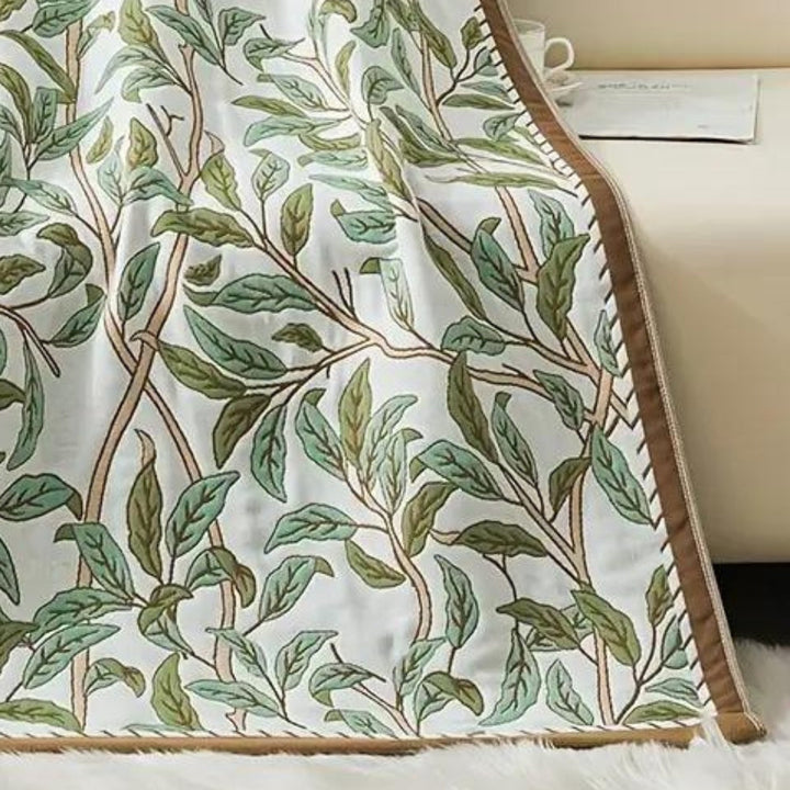White cotton bath towel with a repeating pattern of green and brown branches and leaves.