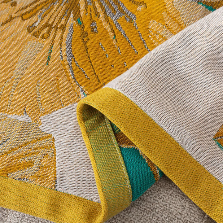 Close-up of a yellow and teal patterned cotton bath towel folded over.