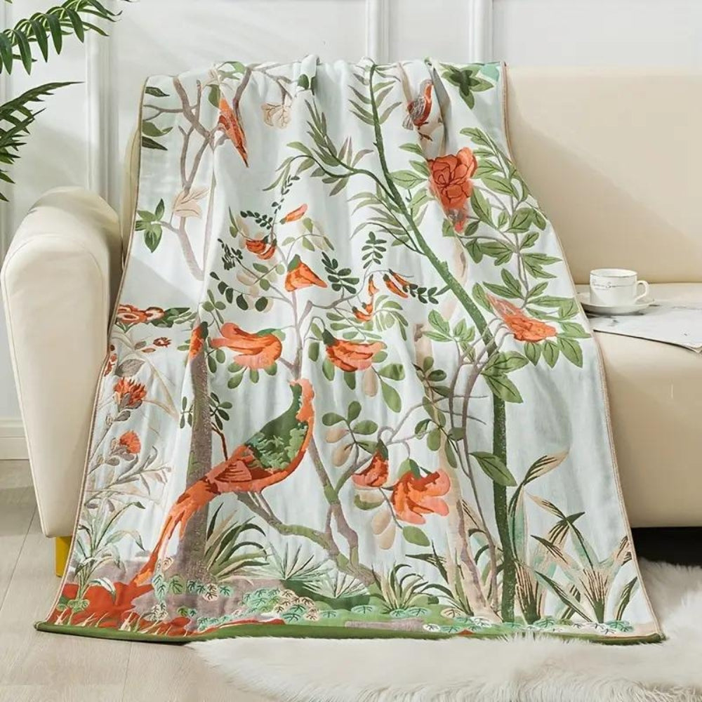 Cotton bath towel with a white background and a vibrant floral and bird print in green, orange, and brown.