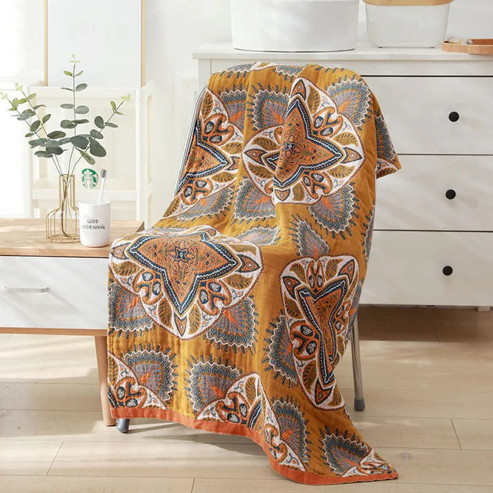 Yellow cotton bath towel with a reversible diamond and floral pattern draped over a chair.