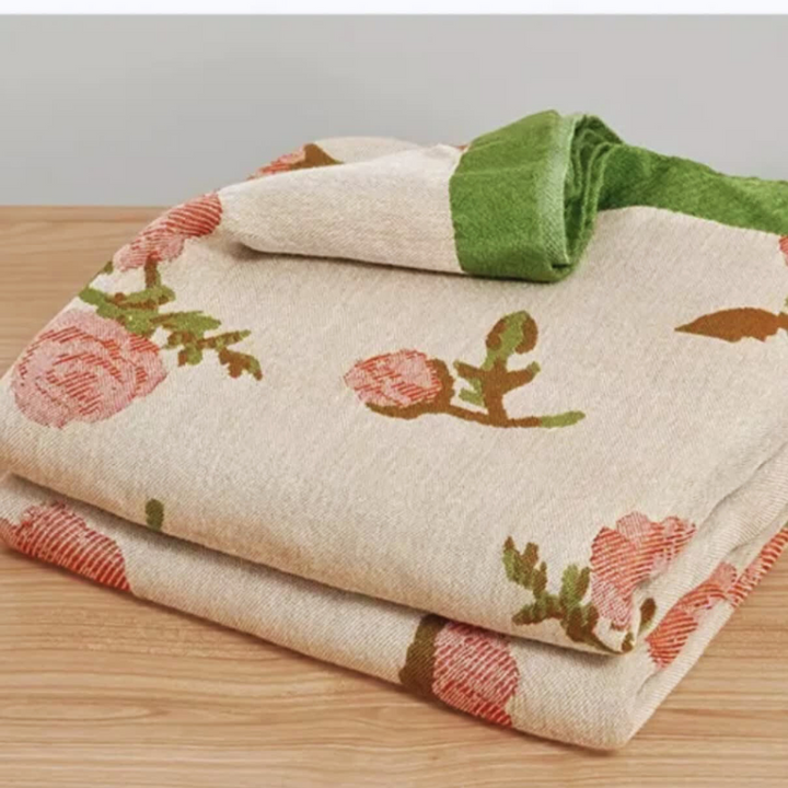 A folded bamboo fiber cooling blanket with a floral rose pattern and a green border.