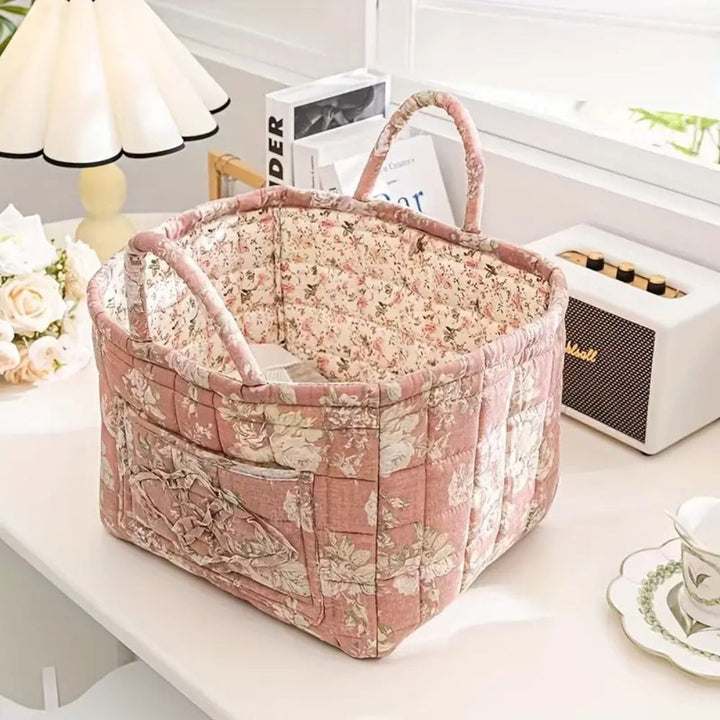 Pink floral canvas storage basket with handles and exterior pockets.