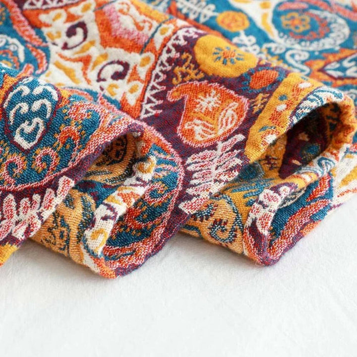 Close-up of a colorful boho-patterned cotton bath towel with intricate geometric and floral designs in shades of blue, orange, and yellow.