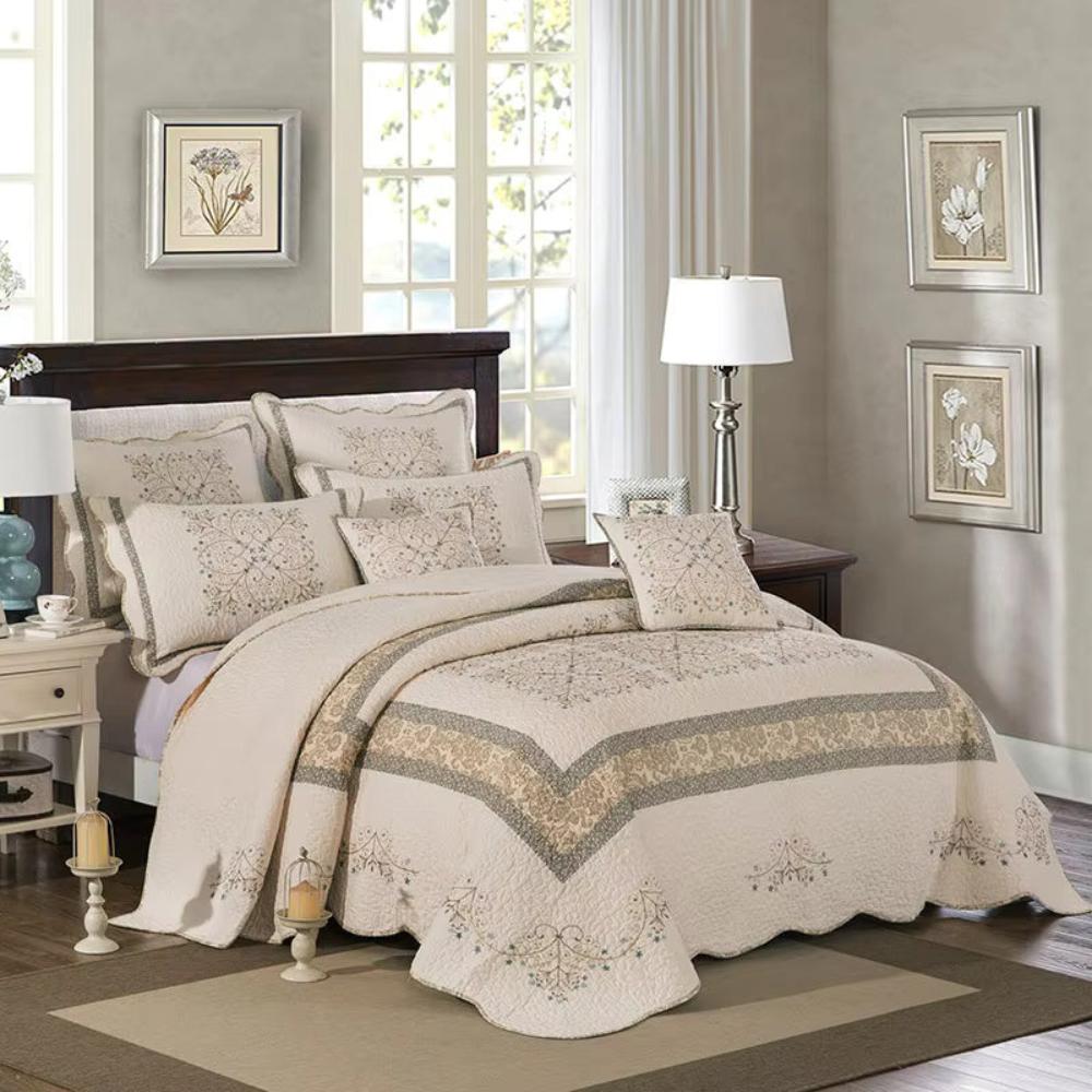Elegant embroidered patchwork thread coverlet on a bed with decorative pillows and lamps.