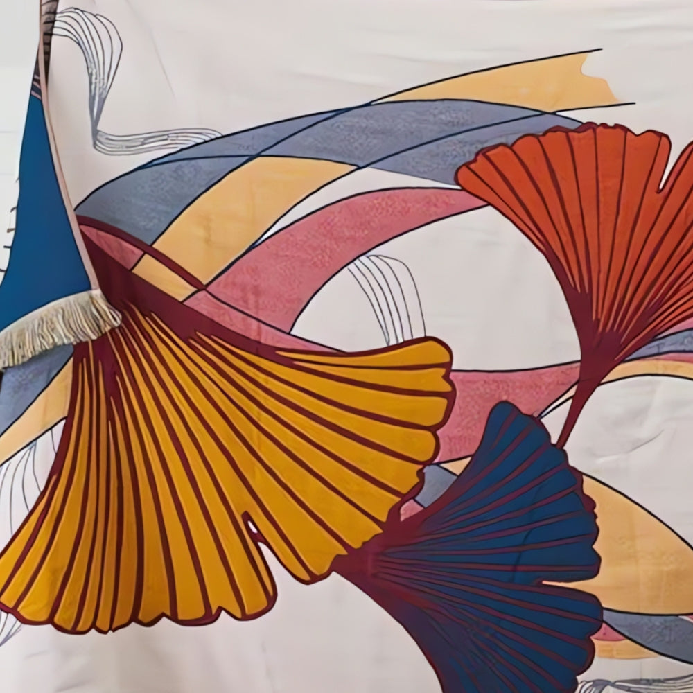 Cotton gauze bath towel with a ginkgo leaf print in yellow, orange, and blue, and a blue tassel edge.