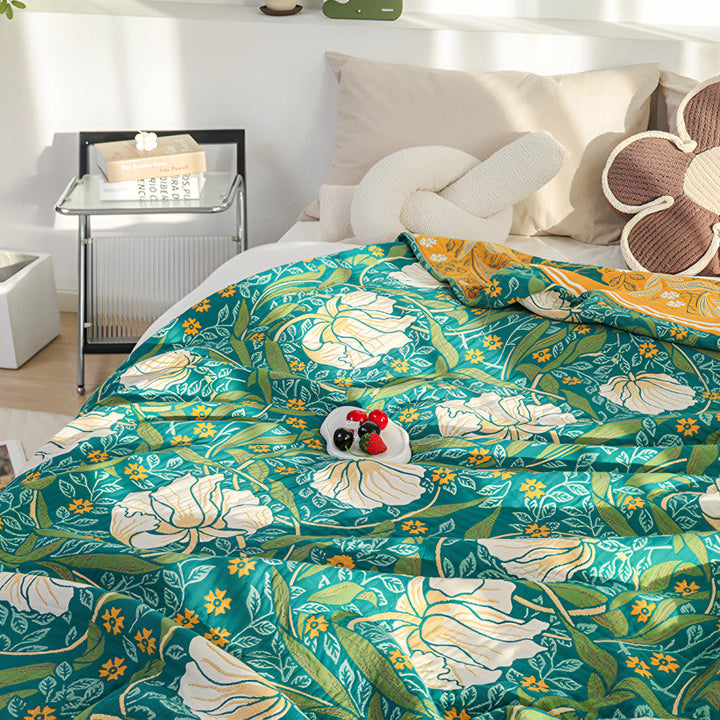 Green botanical bloom cotton blanket with white and yellow flowers and green leaves.