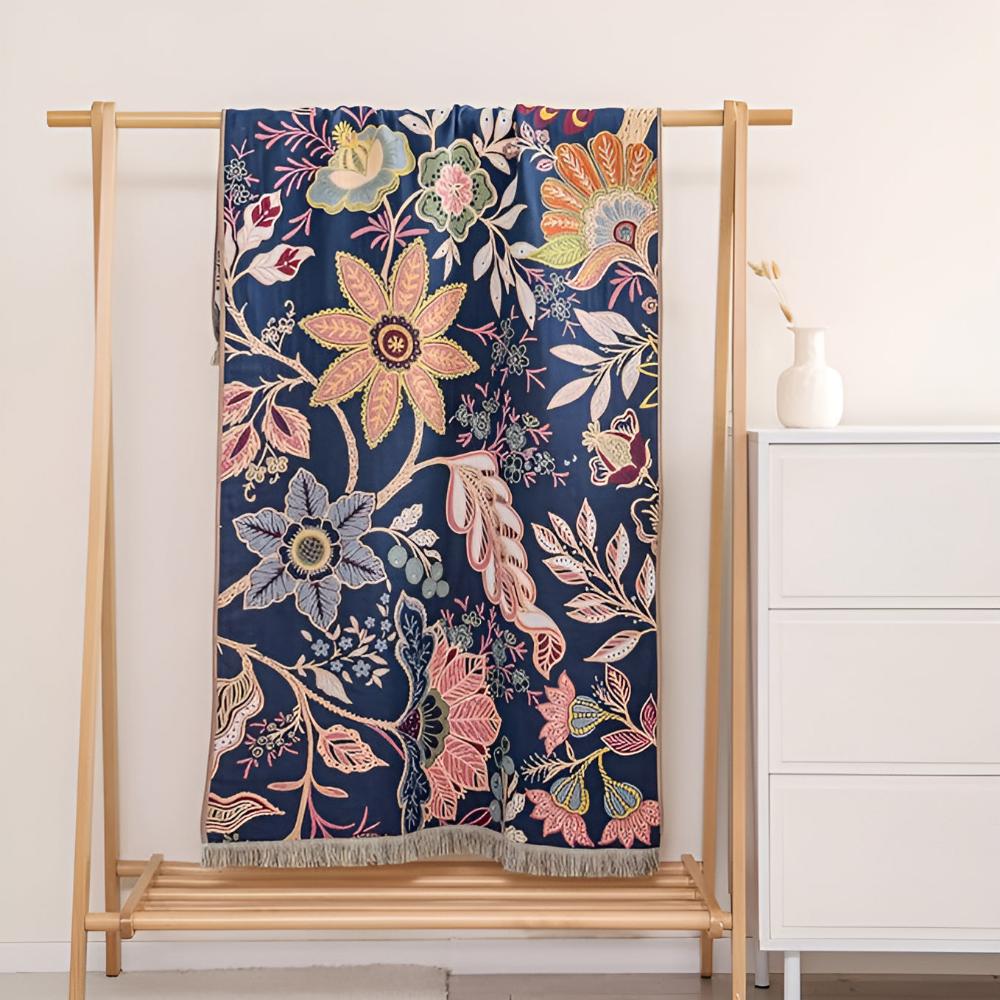 Navy blue cotton towel with a vibrant floral print in pink, orange, and blue, hanging on a wooden rack.