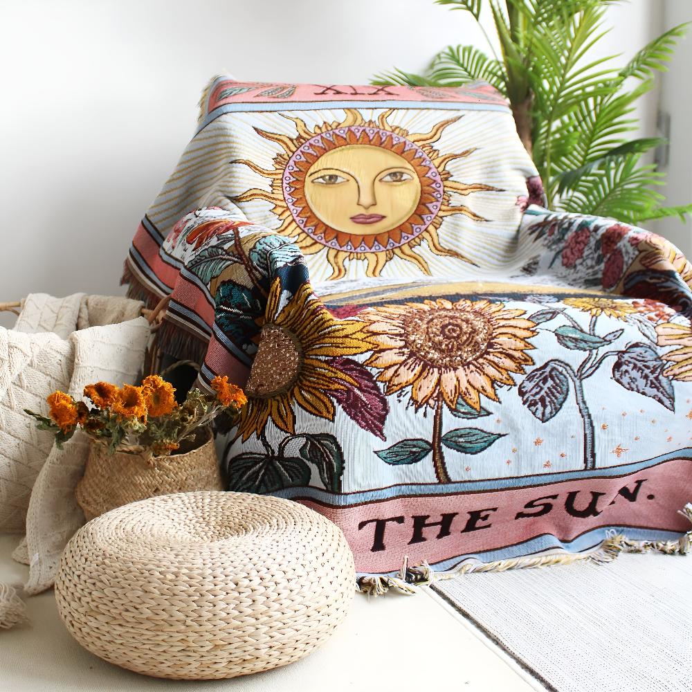 Boho tapestry throw with a celestial sun and sunflowers design draped over a chair.