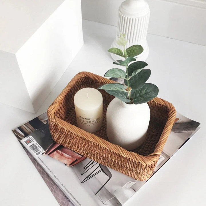 Artisan Rattan Storage Basket with a candle and a small vase with a plant.