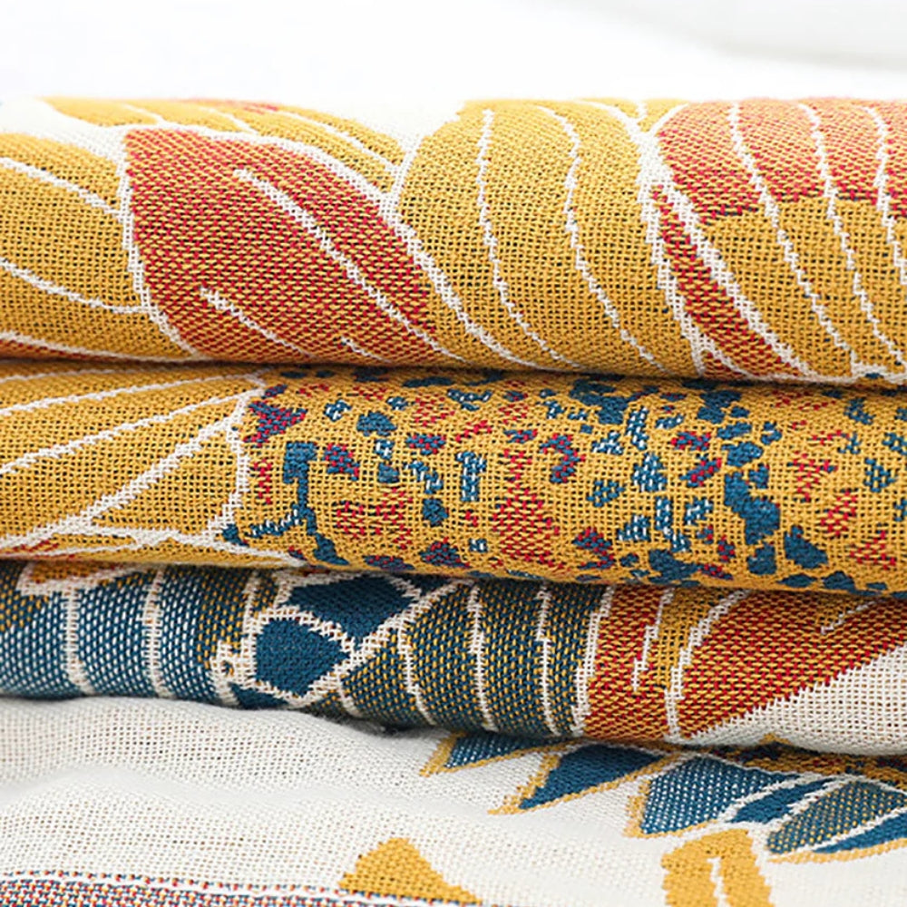 Stack of four folded cotton towels with woven patterns in yellow, red, blue, and white.
