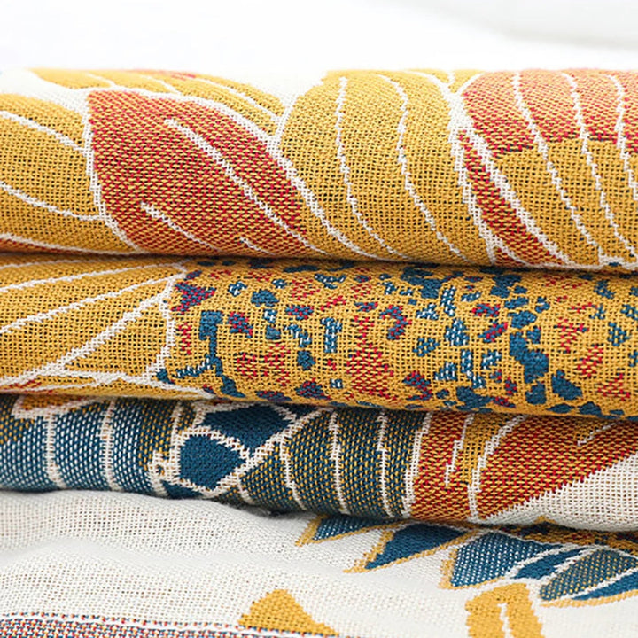 Stack of four folded cotton towels with woven patterns in yellow, red, blue, and white.