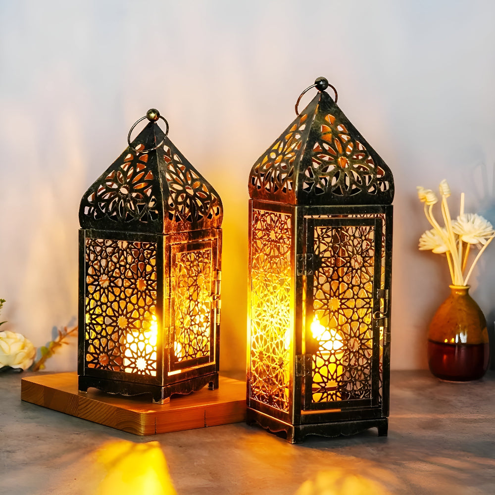 Two antique iron candle holders with intricate geometric cutouts, lit from within.