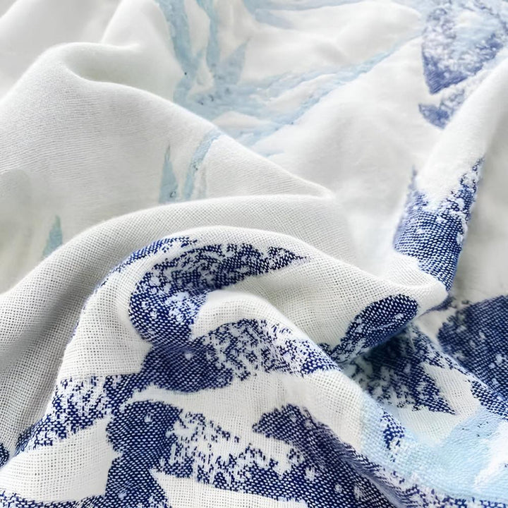 A close-up of a white throw blanket with a blue wave-like pattern.
