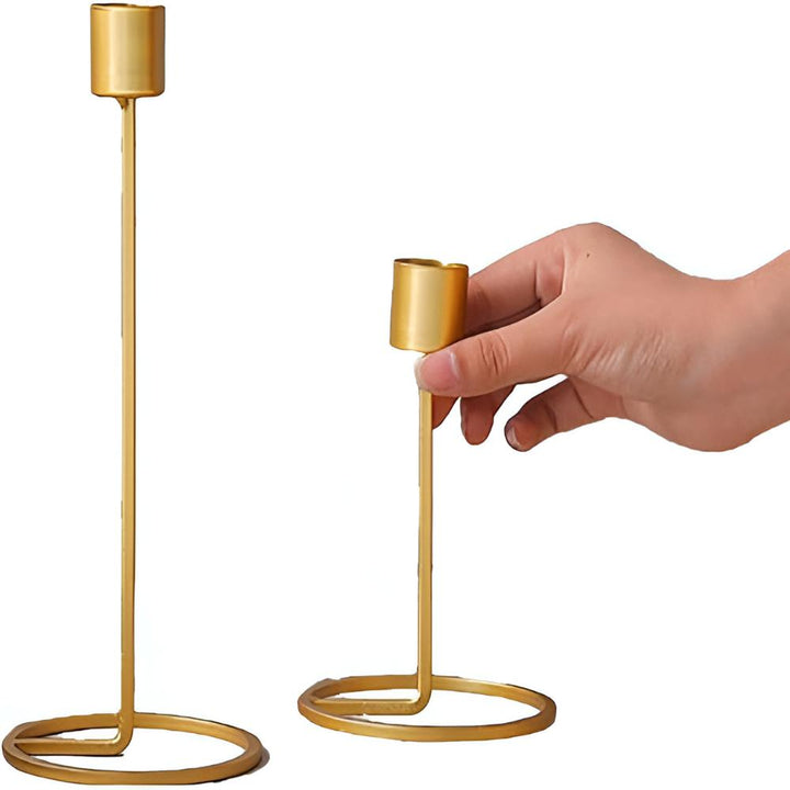 Two golden boho candle holders, one held by a hand, on a white background.