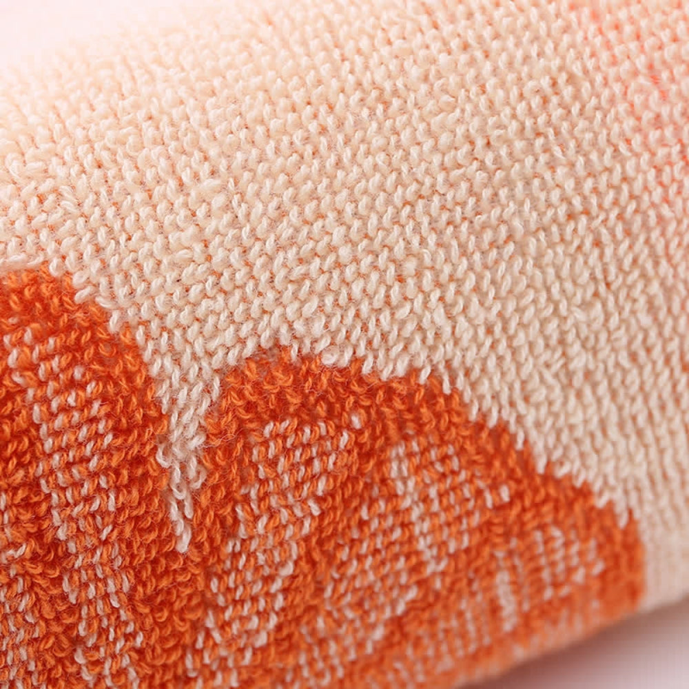 Close-up of a soft, pure cotton bath towel with an orange and white ginkgo leaf pattern.