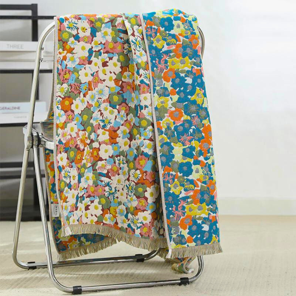 Reversible cotton bath towel with a colorful floral pattern draped over a chair.