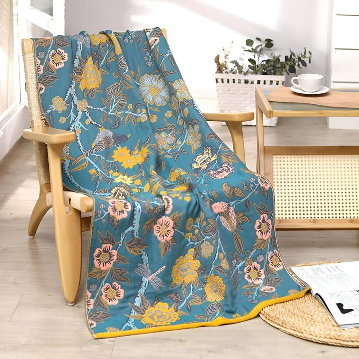Blue cotton towel with a floral and bird print draped over a wooden chair.