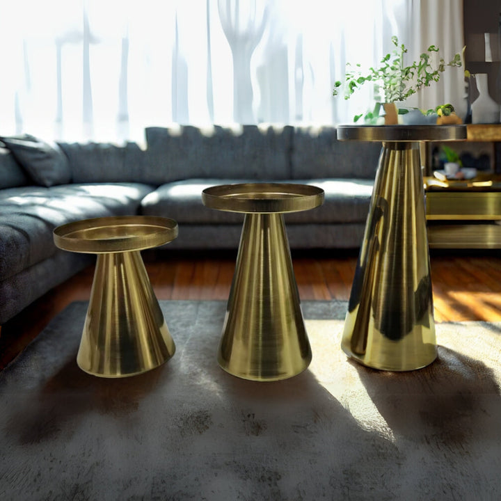 Three conical brass candle holders of varying sizes on a rug in a living room.